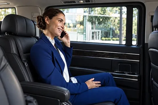 Passagère en tenue professionnelle parlant au téléphone à l’arrière d’un van.