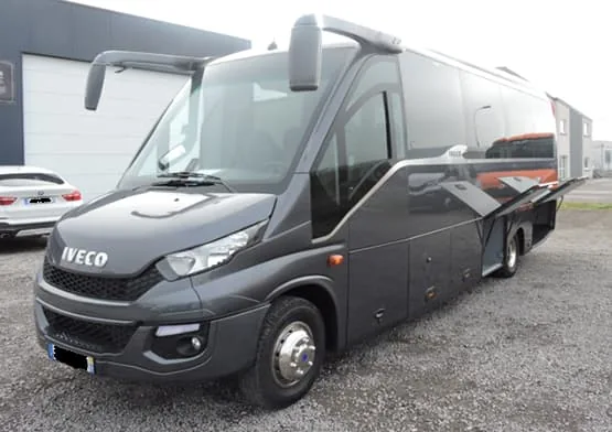 Minibus Iveco gris stationné devant un bâtiment.